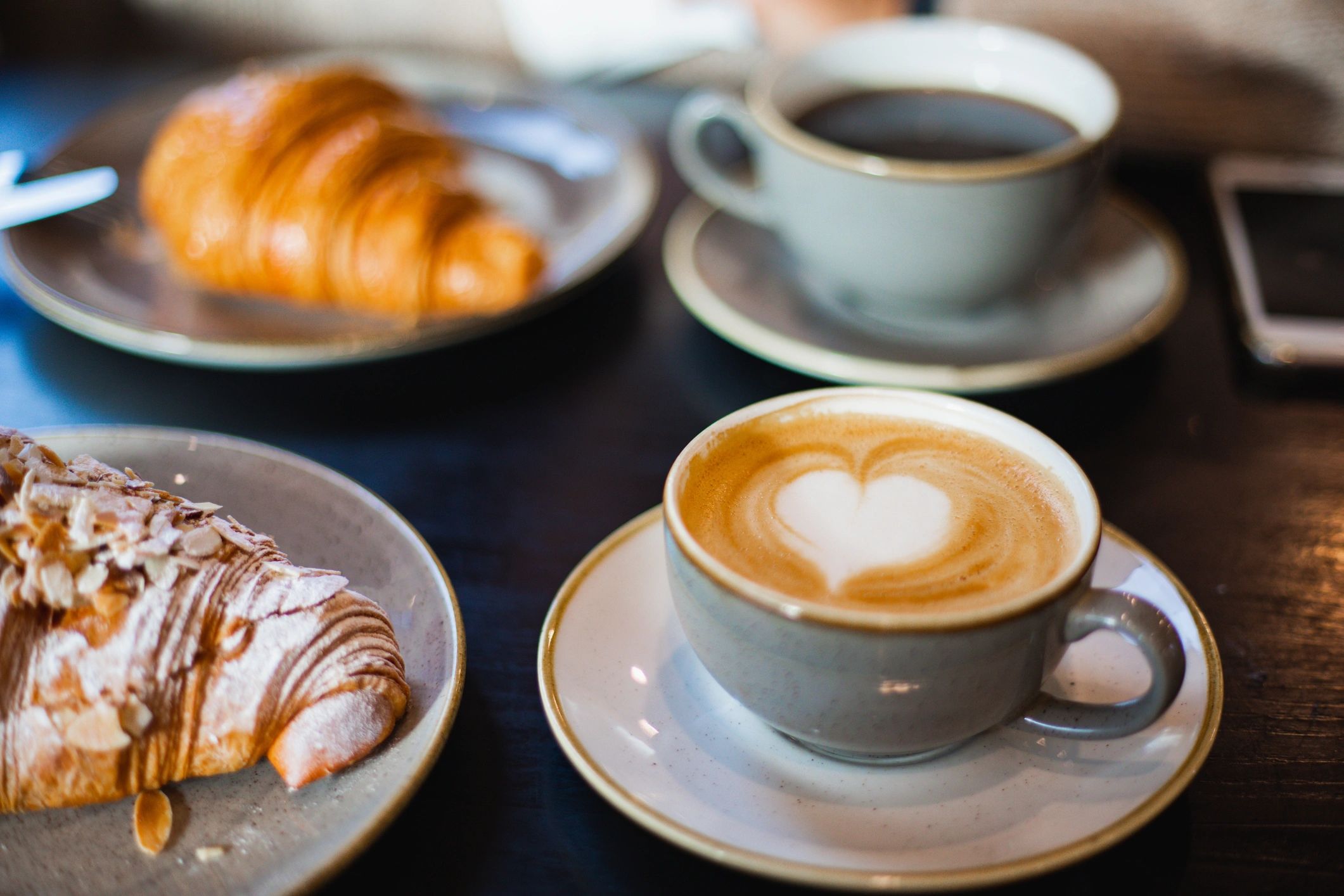 Café breakfast spread with latte art and pastries